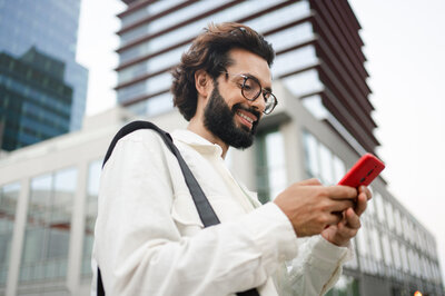 Kontakt zum Kundenservice Ein Mann ruft mit seinem Handy den Kontakt der HUK-Autowelt an.